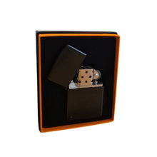 Black flip-top lighter with metallic accents in a black box on a white background