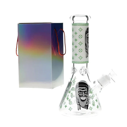 Glass glow in the dark bong with a gorilla design with green accents with colourful packaging on a white background.